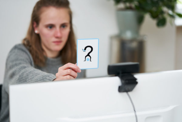 Frau hält Karte mit Fragezeichen in die Kamera
